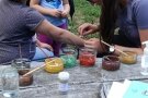 Hände schminken einen Kinderunterarm mit Erdfarben