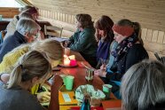 Frauen bei Kerzenschein an einem Tisch in der Hütte. Sie dichten für ihre Aufgabe.