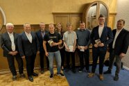 Neun Personen stehen nebeneinander und schauen in die Kamera