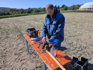 Mann teste Bodenprobe auf Acker an Tisch mit verschiedenen Utensilien