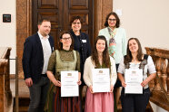 Drei Frauen mit Urkunden im Vordergrund, dahinter ein Mann und zwei Lehrerinnen.