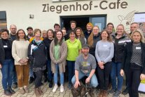 Personengruppe vor Gebäude mit Aufschrift 'Ziegenhof-Cafe'