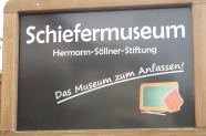 Schild mit der Aufschrift: Schiefermuseum - Herrmann-Söllner-Stiftung - Das Museum zum anfassen!